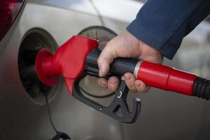A hand holds a pistol for refueling with gasoline. photo