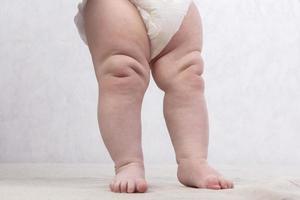 piernas de un rechoncho recién nacido bebé en un pañal foto