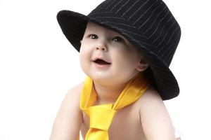 Smiling kid in a retro hat and tie on a white background. Funny six month old baby in elegant clothes. photo