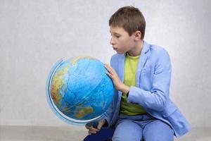 A boy in a suit carefully examines the globe. photo