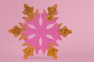 Festive Christmas background. On a pink background, a minimalistic pink large snowflake with gold glitter. photo