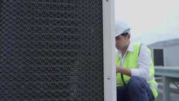 Asian maintenance engineer works on the roof of factory. contractor inspect compressor system and plans installation of air condition systems in construction. technology, online checking video