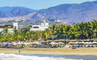 Puerto Escondido Oaxaca Mexico 2023 People parasols sun loungers beach waves palms Zicatela Mexico. photo
