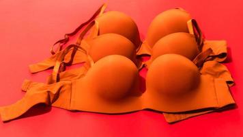 Set of orange color bra on red background, closeup photo