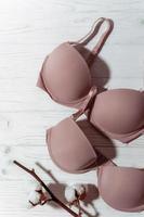 Pink bra with cotton brunch on white wooden background, closeup photo