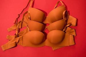 Set of orange color bra on red background, closeup photo