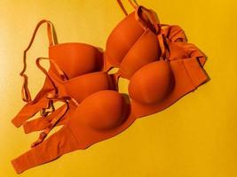 Set of orange color bra on yellow background, closeup. photo