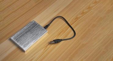 Top view of silver external hard drive laying on wooden background photo