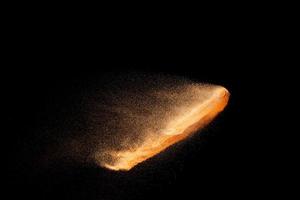 Brown sand explosion isolated on black background. Freeze motion of sandy dust splash. photo