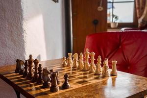 Closeup of brown and white chess pieces arranged on chessboard in hotel photo