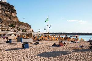 turistas disfrutando verano fiesta a playa con azul cielo y rocoso acantilado foto