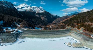 Aerial view of the water dam and reservoir lake in Swiss Alps mountains producing sustainable hydropower photo