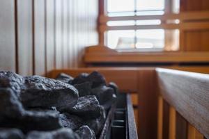 Close-up of black hot stones in heating pot by wooden bench in sauna room photo