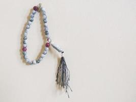selective focus on prayer beads hanging on white background wall with copy space photo