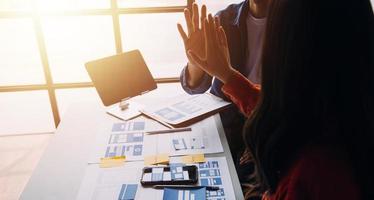 Close up ux developer and ui designer brainstorming about mobile app interface wireframe design on table with customer breif and color code at modern office.Creative digital development agency photo