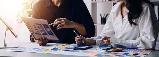 Close up ux developer and ui designer brainstorming about mobile app interface wireframe design on table with customer breif and color code at modern office.Creative digital development agency photo