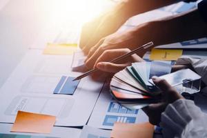 Close up ux developer and ui designer brainstorming about mobile app interface wireframe design on table with customer breif and color code at modern office.Creative digital development agency photo