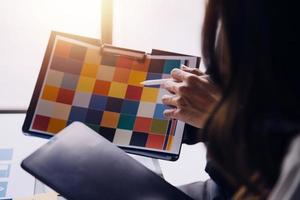 Close up ux developer and ui designer brainstorming about mobile app interface wireframe design on table with customer breif and color code at modern office.Creative digital development agency photo