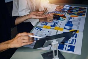 Close up ux developer and ui designer brainstorming about mobile app interface wireframe design on table with customer breif and color code at modern office.Creative digital development agency photo
