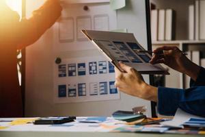 Close up ux developer and ui designer brainstorming about mobile app interface wireframe design on table with customer breif and color code at modern office.Creative digital development agency photo