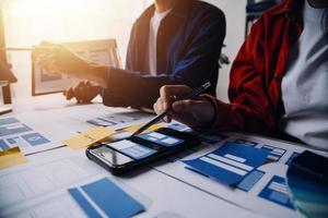 Close up ux developer and ui designer brainstorming about mobile app interface wireframe design on table with customer breif and color code at modern office.Creative digital development agency photo