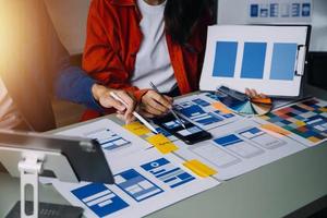 Close up ux developer and ui designer brainstorming about mobile app interface wireframe design on table with customer breif and color code at modern office.Creative digital development agency photo