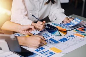Close up ux developer and ui designer brainstorming about mobile app interface wireframe design on table with customer breif and color code at modern office.Creative digital development agency photo