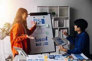 Close up ux developer and ui designer brainstorming about mobile app interface wireframe design on table with customer breif and color code at modern office.Creative digital development agency photo