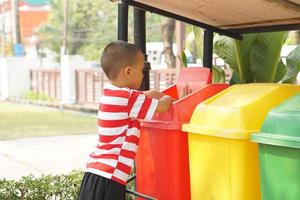 Boy looking at trash cans in the garden photo