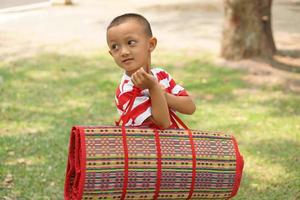 boy holding Mats for sitting in the garden photo