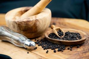 many black peppercorns on olive wood photo