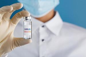 Virus Vaccine on an ampoule in the hands of a scientist doctor in rubber gloves with a vaccine close-up. photo