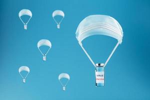 Ampoules with a vaccine against coronavirus infection and viruses dropped by parachute from a protective mask on a blue background. photo