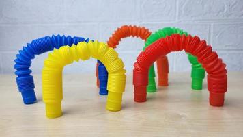 A set of funny plastic multicolored tubes-antistress on a wooden background photo