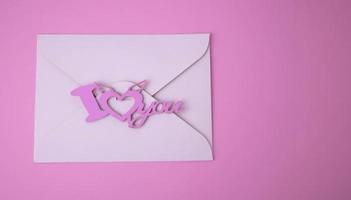 White envelope for Valentine's Day on a pink background. The concept of a love message for March 8, Mother's Day, Father's Day, Family Day photo