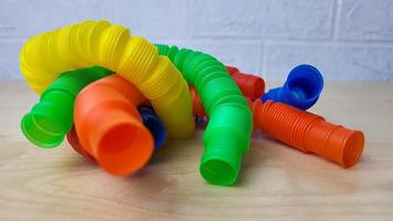 A set of funny plastic multicolored tubes-antistress on a wooden background photo