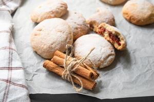 Round apple cookies and string tied cinnamon sticks on greaseproof baking paper photo