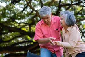 Asian senior man falling down on lying floor at park after Stumbled  and Crying in pain and him wife came to help support. Concept of old elderly insurance and health care photo