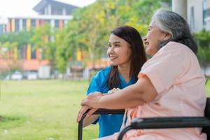 Asian careful caregiver or nurse hold the patient hand and encourage the patient in a wheelchair.  Concept of happy retirement with care from a caregiver and Savings and senior health insurance. photo