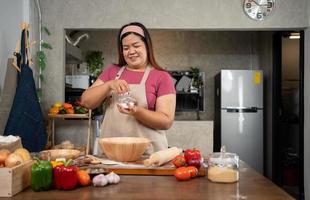 retrato de obeso mujer Cocinando Pizza en el cocina, crudo Pizza en el manos de un ama de casa. hecho en casa Pizza Cocinando en el cocina a hogar. aprendizaje cómo a hacer sabroso Pizza cena almuerzo foto