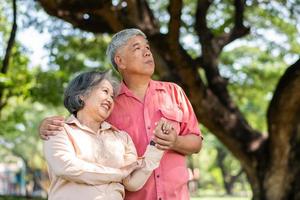 Portrait of lovely elderly couple hugging each other with love and happiness in a park outdoor. Happy smiling Elderly couple enjoying with positive emotions at garden photo