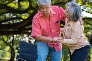 Asian senior man falling down on lying floor at park after Stumbled  and Crying in pain and him wife came to help support. Concept of old elderly insurance and health care photo