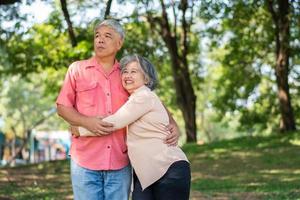 Portrait of lovely elderly couple hugging each other with love and happiness in a park outdoor. Happy smiling Elderly couple enjoying with positive emotions at garden photo
