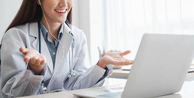 La doctora terapeuta asiática está visitando en línea a un paciente en la aplicación de Internet. ella escucha y da consejos y explica cómo tratar la enfermedad inicial, concepto de tecnología médica. foto