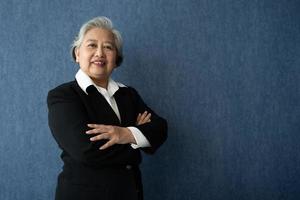 Portrait of middle aged business woman standing isolated on blue background and folded arms looking at the camera with a smile, Successful businesswoman, ceo, director, manager, banker, hr. photo