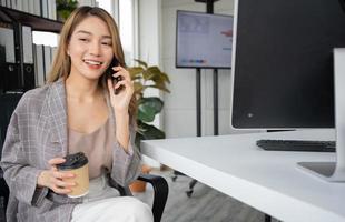 feliz joven emprendedora asiática hablando con su socio o co-inversor y sonriendo después de un exitoso contacto comercial, niña feliz en el lugar de trabajo. aprendizaje a distancia educación y trabajo en línea. foto