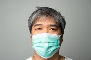 Sick Asian man wearing a medical face mask and Shoulder pain and stress. Concept of protection pandemic coronavirus and respiratory disease photo