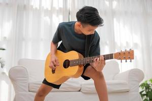 retrato de un asiático contento sonriente chico teniendo divertido jugando guitarra música concepto, niños música escuela. rock concierto, música para niños y niños pequeños concepto foto