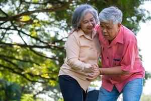 Asian senior man falling down on lying floor at park after Stumbled  and Crying in pain and him wife came to help support. Concept of old elderly insurance and health care photo