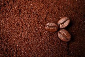 Closeup of three coffee beans at the mixed heap of roasted coffee with copy space for text. Concept of Coffee freshness photo